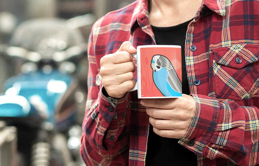 person holding a mug featuring a budgerigar illustration